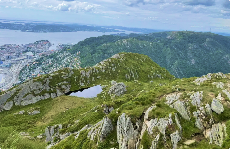 green craggy rocks and mountains near a city and a lake